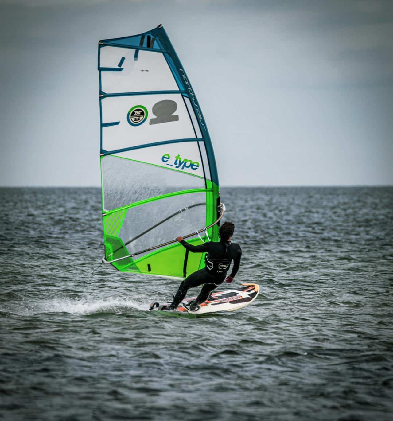 Primer plano de un instructor de Wind & Water Experience realizando una micro-corrección postural a un alumno durante una clínica de perfeccionamiento en Tarifa para mejorar la técnica de planeo.