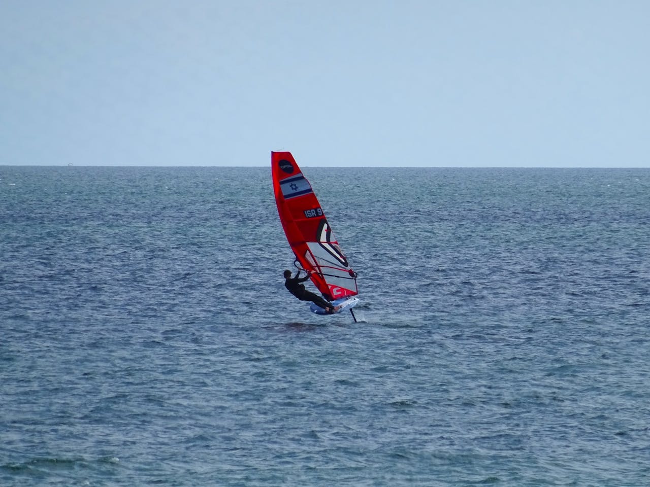 Windsurfista en Tarifa intentando una maniobra avanzada, ilustrando el estancamiento técnico y los vicios posturales comunes que se corrigen con clases de perfeccionamiento.